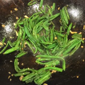 green beans sautéing in a wok