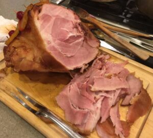 Whole ham with slices on a cutting board.