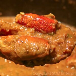 Spoonful of Cajun Crawfish Bisque with two stuffed heads