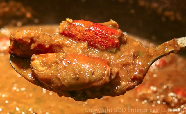 Spoonful of Cajun Crawfish Bisque with two stuffed heads