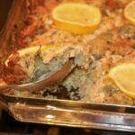 Stuffed Artichoke Casserole-13 Stuffed Artichoke Casserole with lemon slices being spooned out of casserole