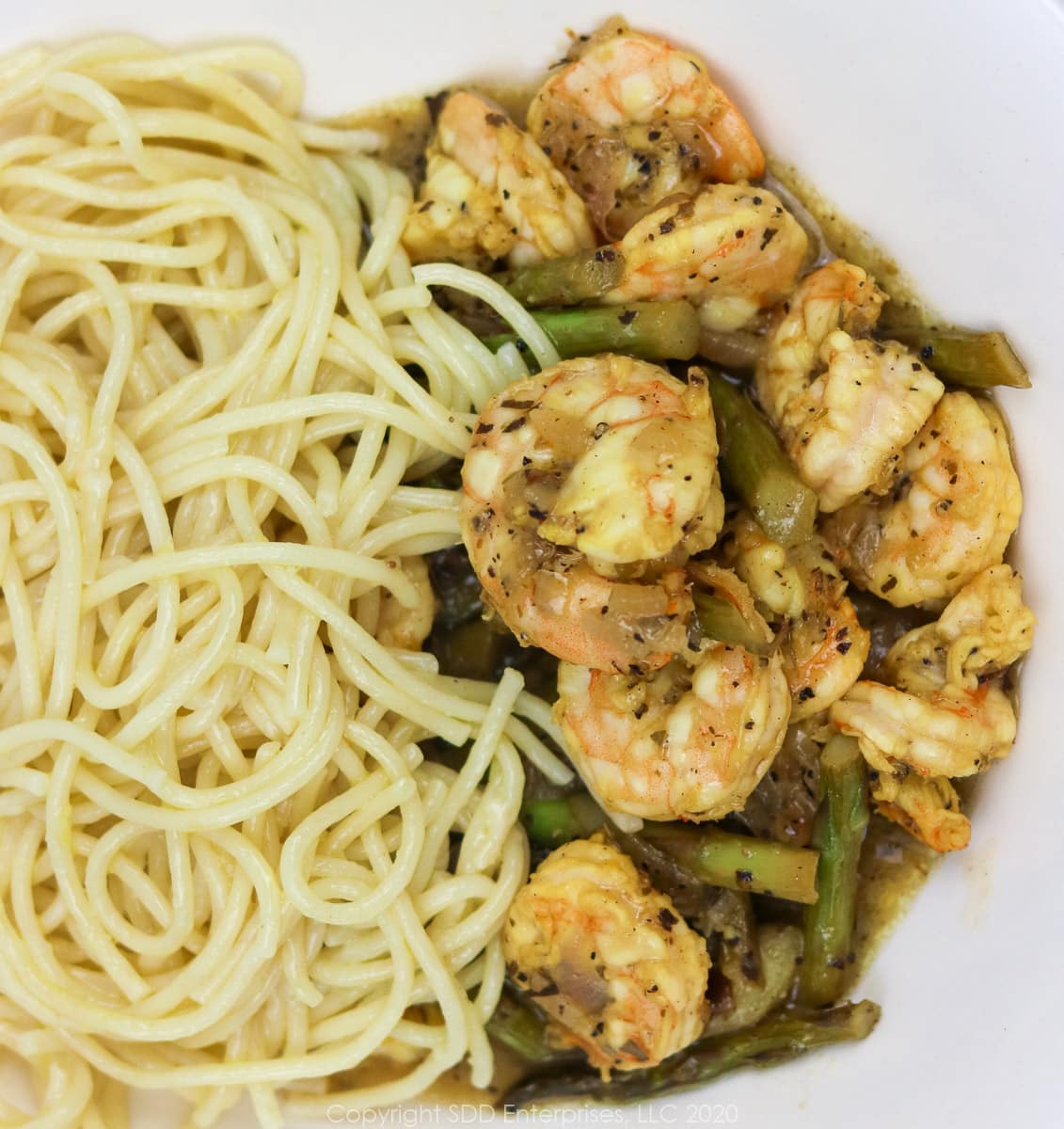 sauteed shrimp and asparagus with pasta in a white bowl