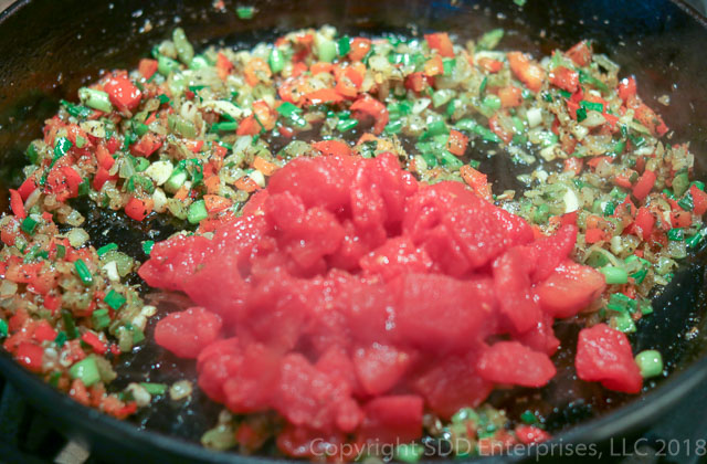adding tomatoes to the trinity and seasoning
