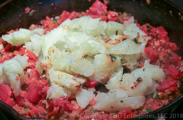 adding mirliton to cooking tomatoes, onions and seasoning