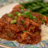 Shrimp Creole on a plate with green onions and green beans