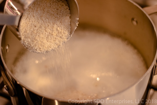 Pouring grits into boiling water