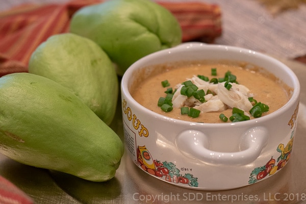 Mirliton Crab Bisque with crab meat in a bowl with three mirlitons