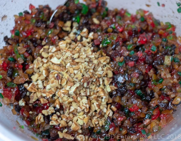 Adding chopped nuts to marinaded candied fruit