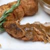 Sliced pork tenderloin with meyer lemon sauce and sprig of fresh rosemary