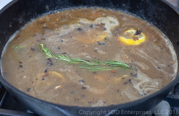 wine , stock, wrcestershire and lemon juice added with sprig of rosemary to the skillet