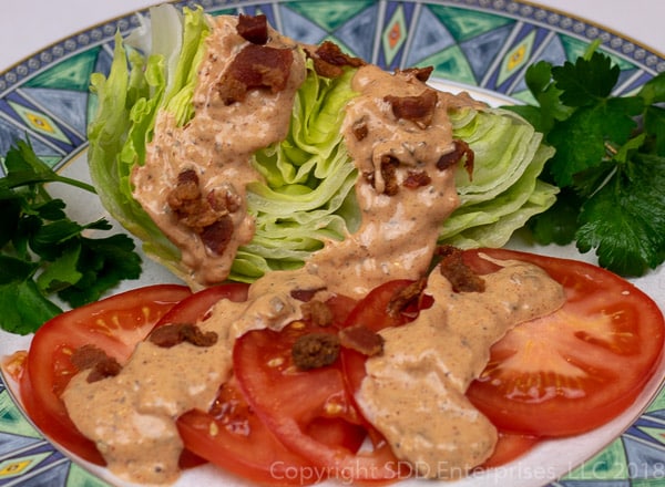 cajun thousand island dressing with bacon bits poured over lettuce and tomatoes