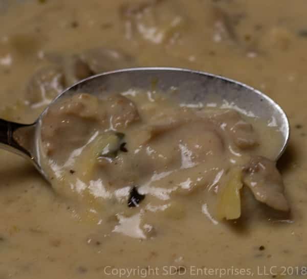 spoon full of oysters and artichokes in oyster artichoke bisque