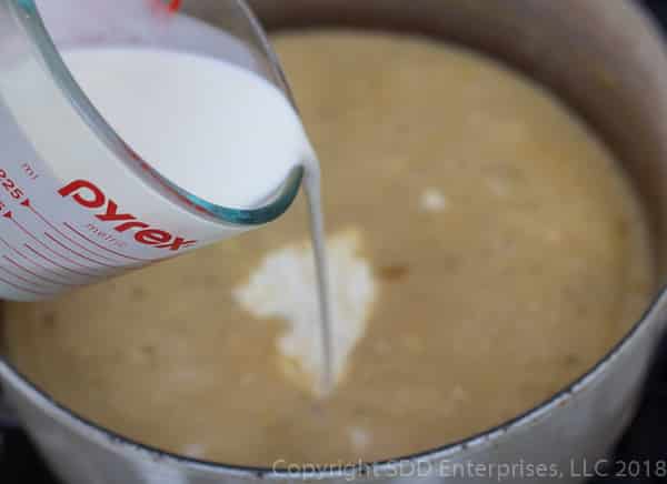 pouring heavy cream into the dutch oven