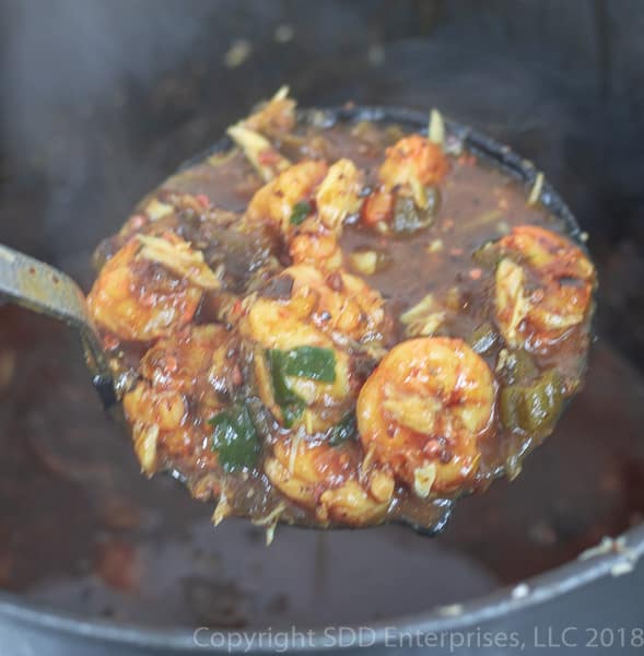 a ladel of shrimp and okra gumbo over a stock pot