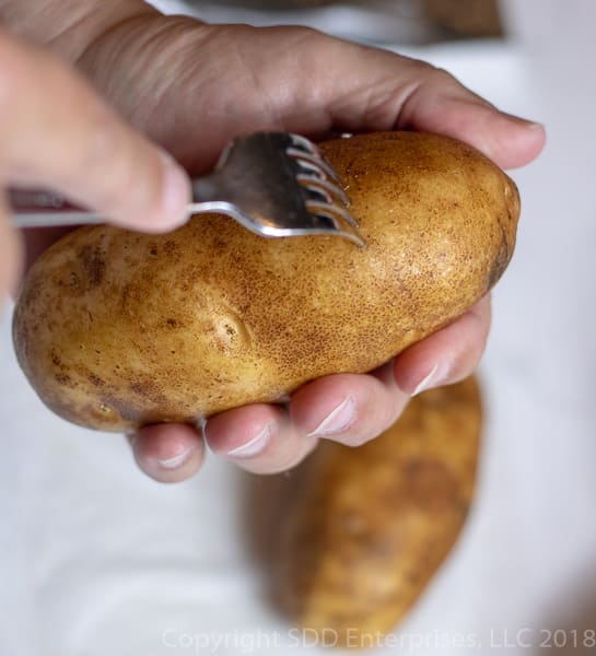 russet potato being poked with a fork.