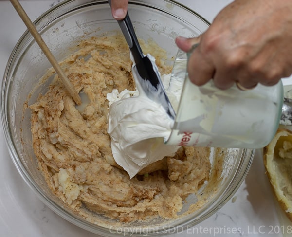 adding sour cream to potatoes with creole seasoning