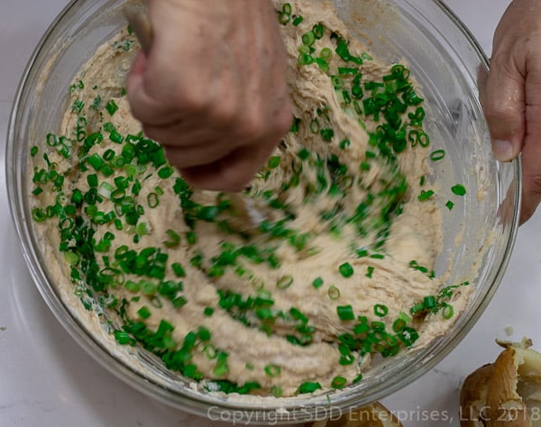 adding green onions to the potatoes