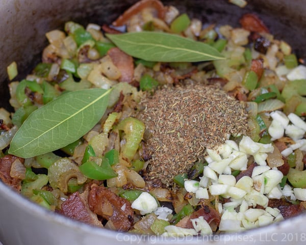 hrebs abd spices and garlic added to frying holy trinity in a dutch oven