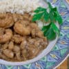 white beans with shrimp in a bowl with rice and parsley garnish