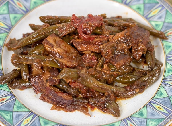 smothered creole green beans served on a plate with green border