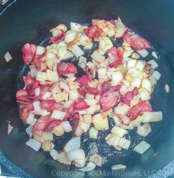 yellow onions sauteing in bacon grease in dutch oven