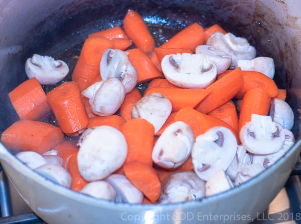 mushrooms and carrots being sauteed in dutch oven