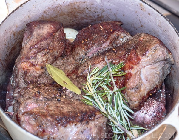 chuck roast with onions and garlic and herbs in dutch oven