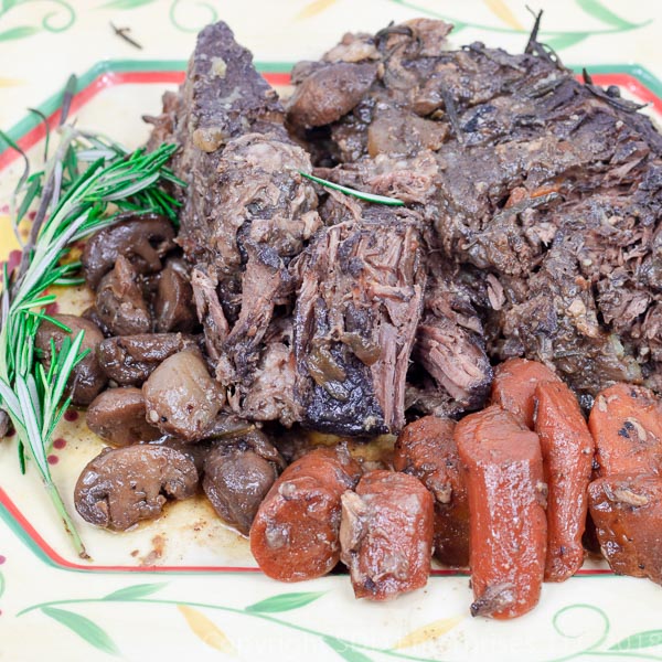 pot roast with carrots and mushrooms and rosemary on a platter