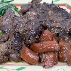 tender pot roast on a platter with carrots, mushrooms and rosemary