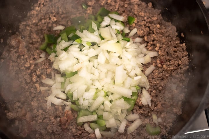 chopped onions, bell peppers and celery added to dutch oven with meats for dirty rice