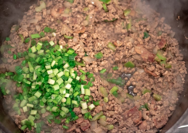 chopped green onions added to the dutch oven with meats for dirty rice