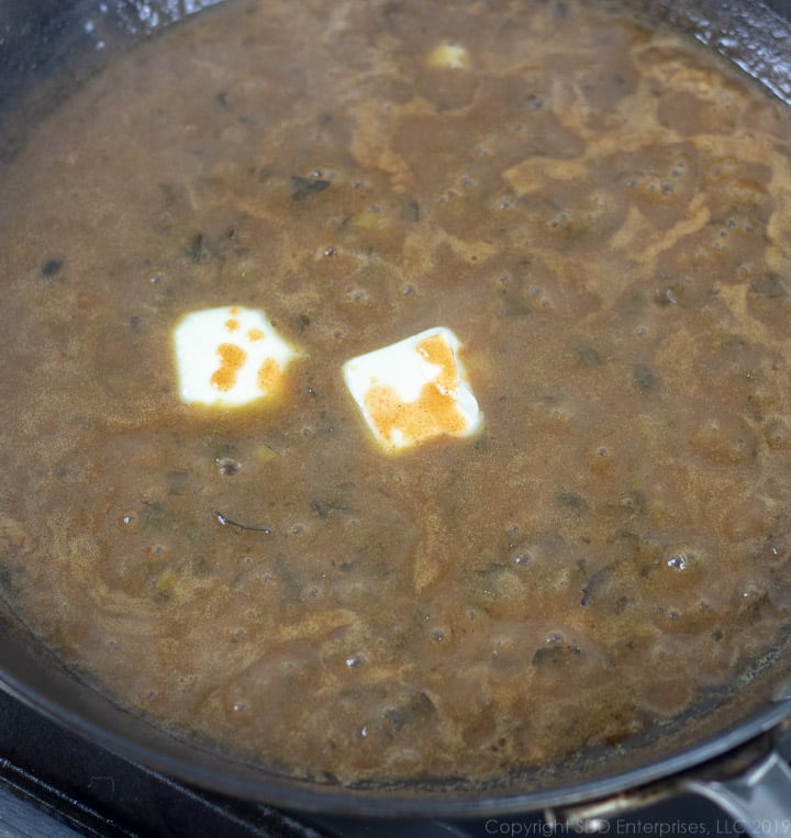 finishing the meuniere sauce with some butter and Tabasco sauce in a cast iron pan