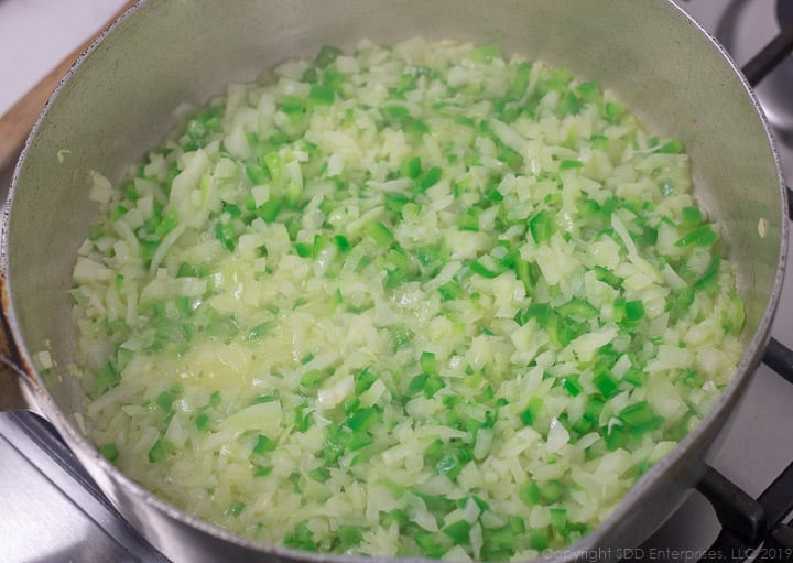 sauteing onions and bell peppers in a frying pan for stuffed bell peppers