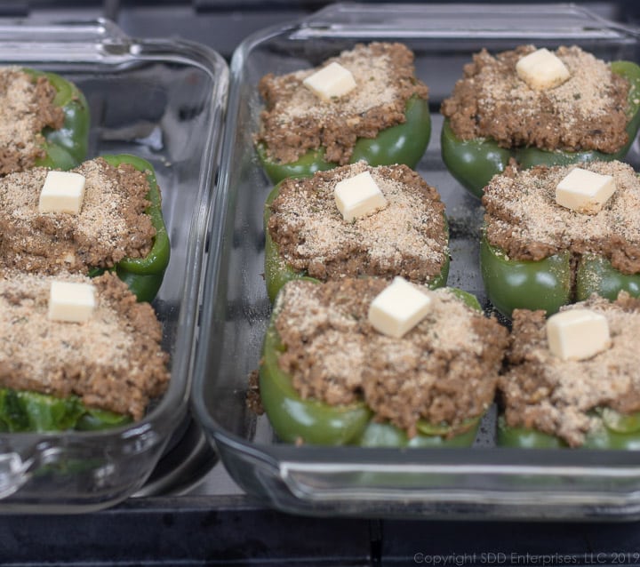 stuffed bell peppers with bread crumb topping in a baking dish ready for oven