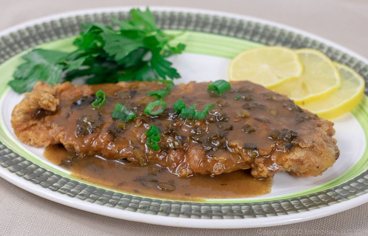 fried trout on a platter with meuniere sauce and garnish