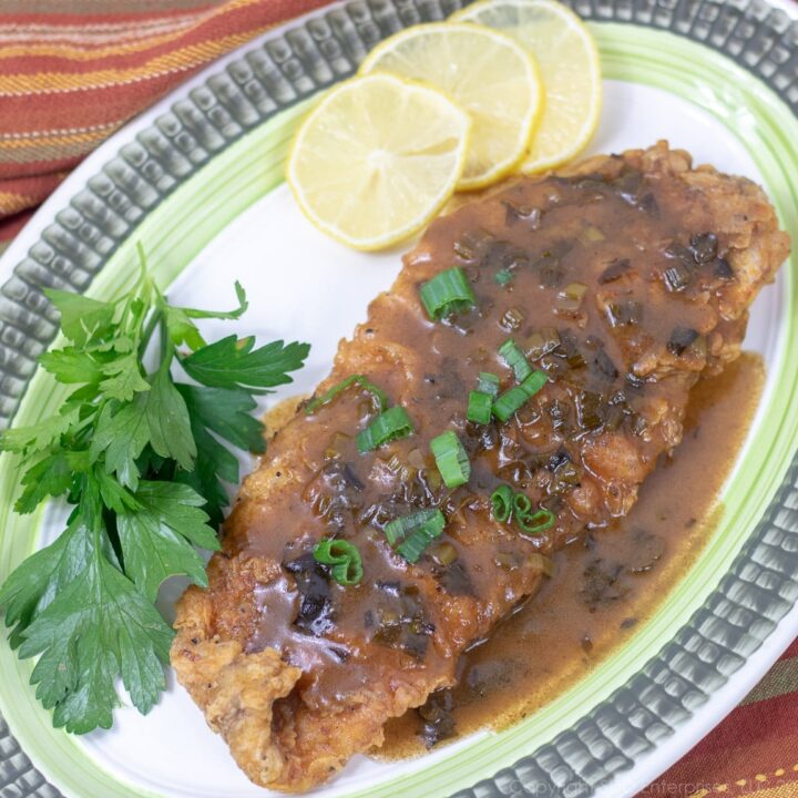 Fried trout with meuniere sauce and garnish on a platter