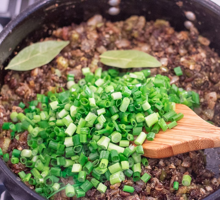 chopped green onions added to the trinity in a frying pan for turkey oyster gumbo