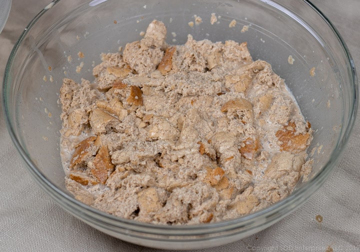 bread pieces soaking in custard in a clear glass bowl for bread pudding