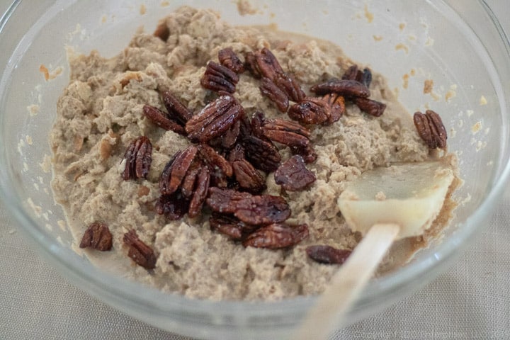 Pecans added to bread pudding mixture in a glass bowl.