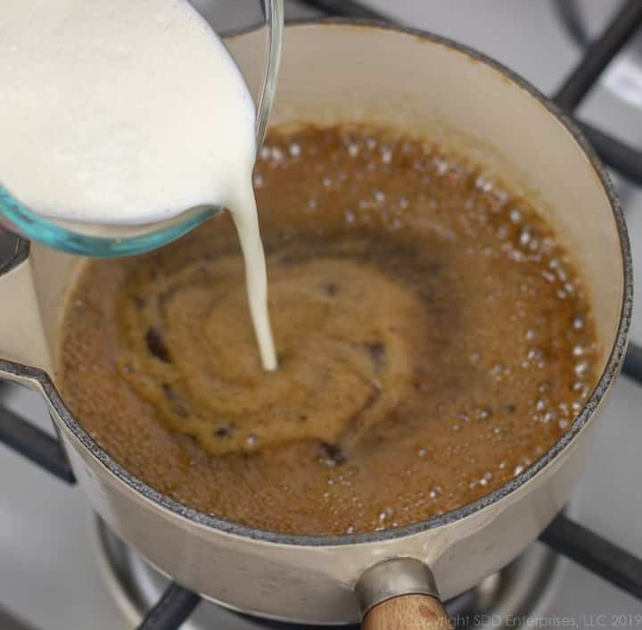 pouring heavy cream into the sauce pan for cane sugar rum sauce