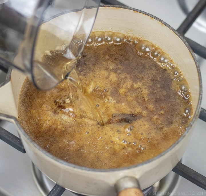 pouring rum into sauce pan with cane syrup rum ingredients