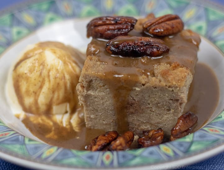 bread pudding with cane syrup rum sauce and glazed pecans with vanilla ice cream in a bowl with green trim