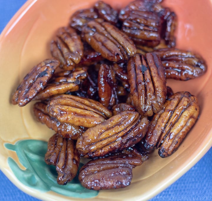 glazed pecans with rum and cane syrup in a small orange and green bowl