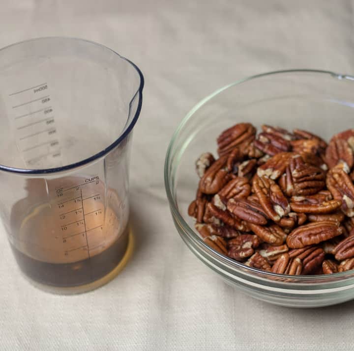 pecan halves in a bowl with a measure of dark rum