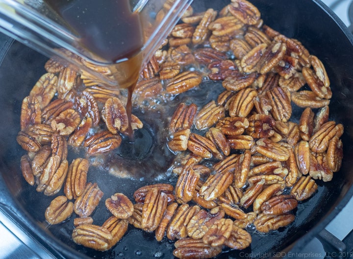 marinated pecan halves in a cast iron skillet with butter