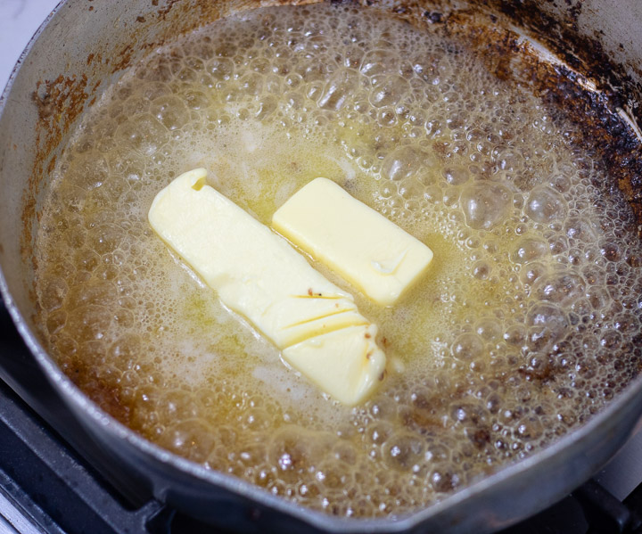 melting butter in pork sausage grease in a frying pan for oyster dressing