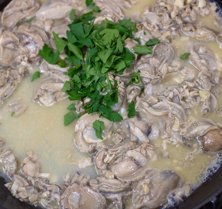 oysters with parsley sauteing in a skillet for oyster dressing