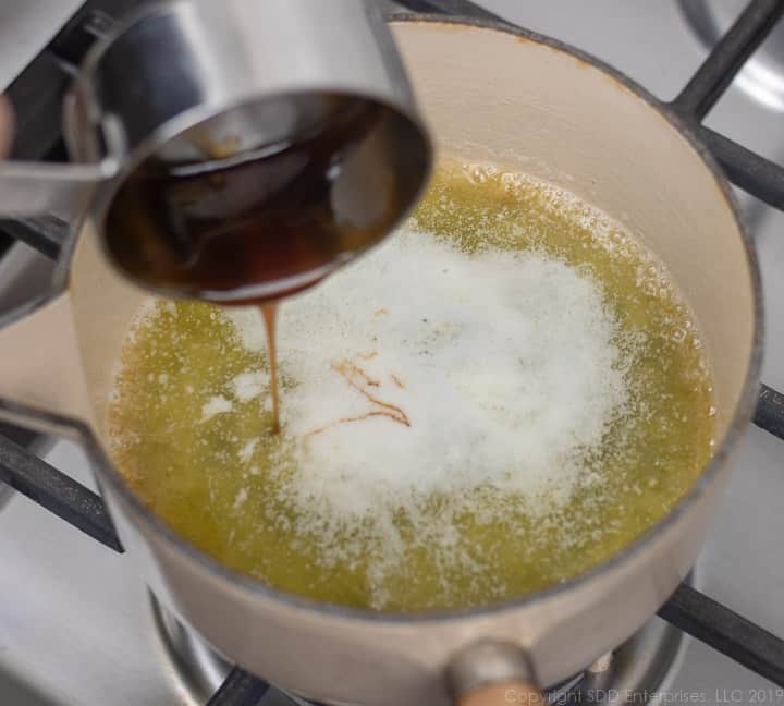cane syrup being added to melted butter ina sauce pan for cane syrup rum sauce for bread pudding