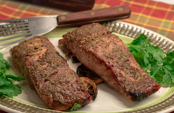 grilled cilantro creole mustard marinated salmon on a platter with parsley garnish and a fish skimmer