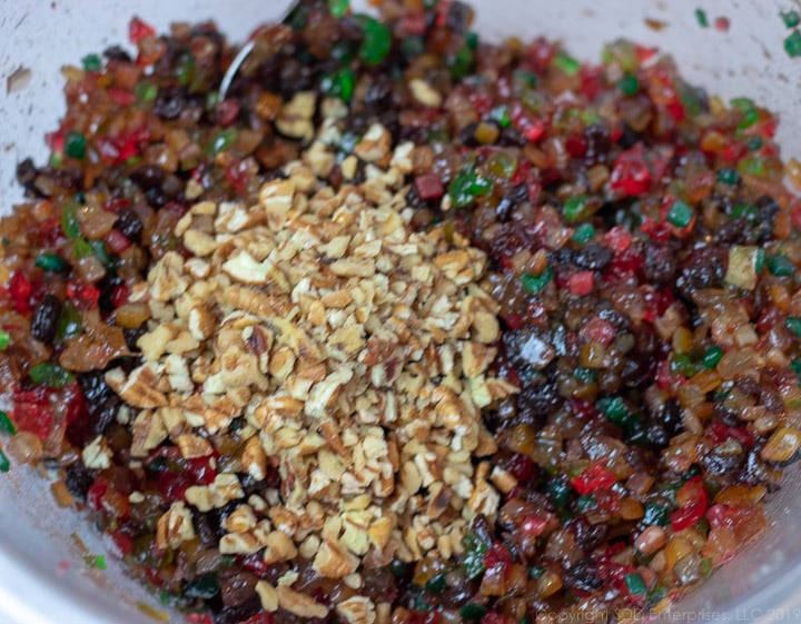 Chopped nuts and marinated fruit in a glass bowl for fruitcake.